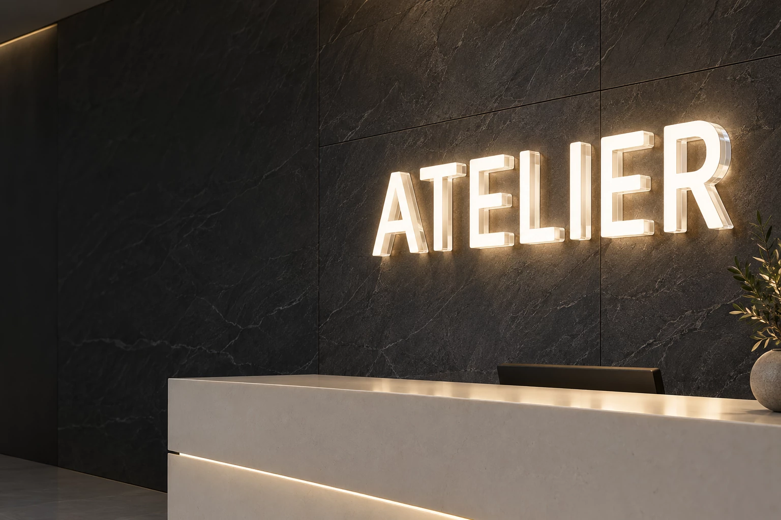 Large white acrylic LED ATELIER letters with illuminated faces and sides on a dark reception wall