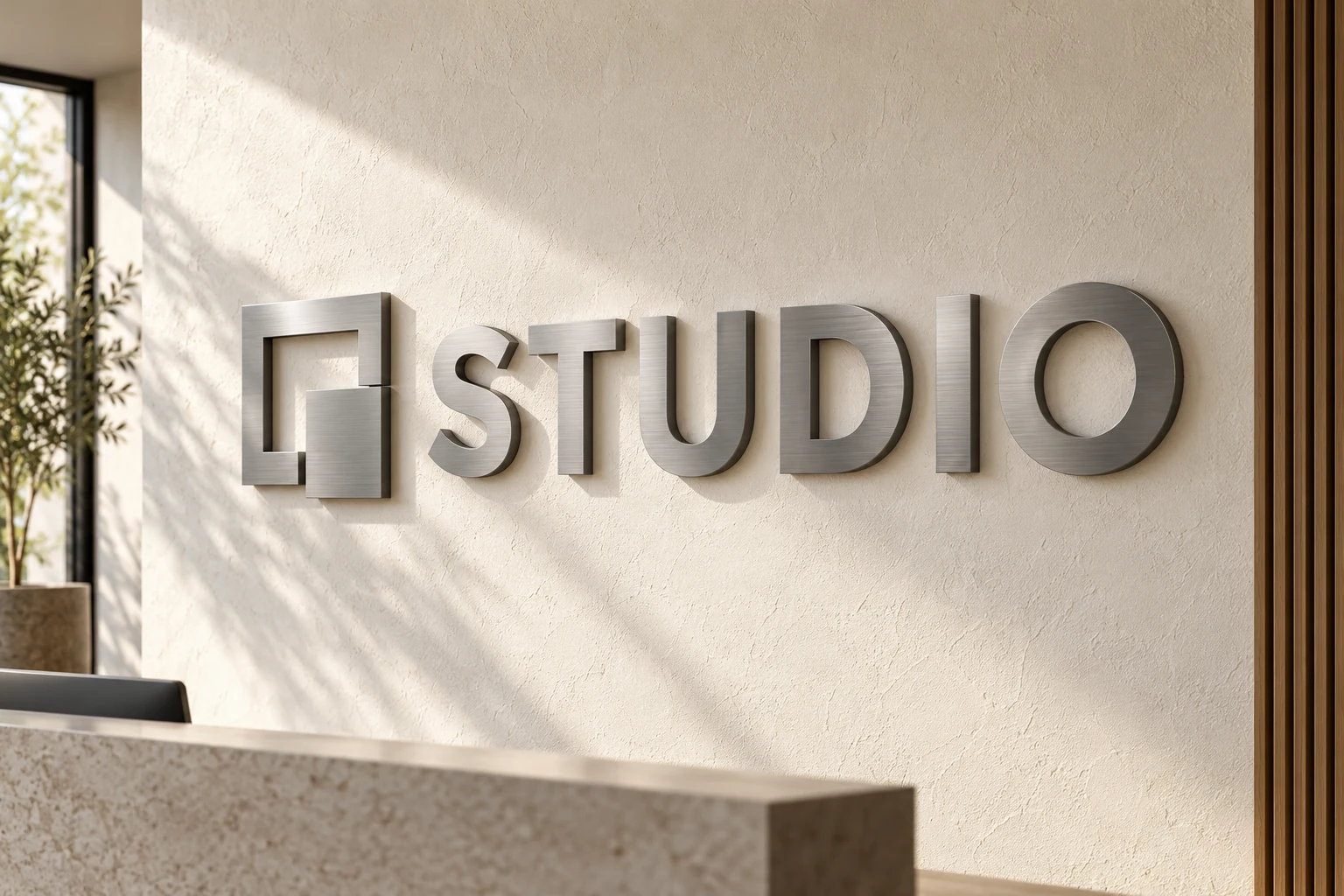 Brushed metal STUDIO letters and geometric logo mounted on a textured reception wall